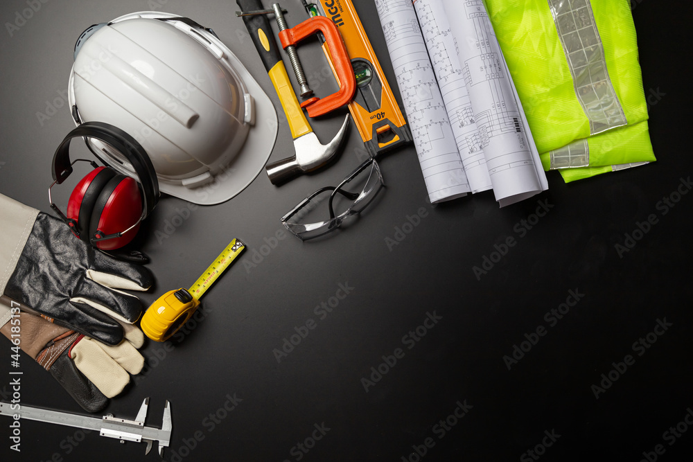 Work safety. Construction site protective equipment on wooden background, flat lay, copy space, top view Work safety. Construction site protective equipment on wooden background, flat lay, copy space, top view