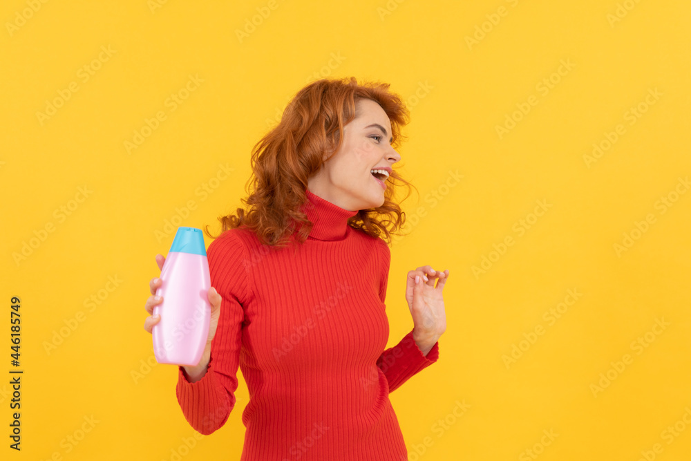 happy redhead girl curly dyed hair presenting body care product of shampoo having fun, cosmetics happy redhead girl curly dyed hair presenting body care product of shampoo having fun, cosmetics