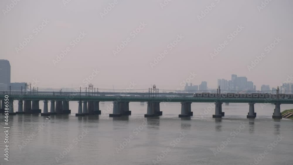 Wide establishing shot of a train travelling on a bridge over a river in Asia Wide establishing shot of a train travelling on a bridge over a river in Asia
