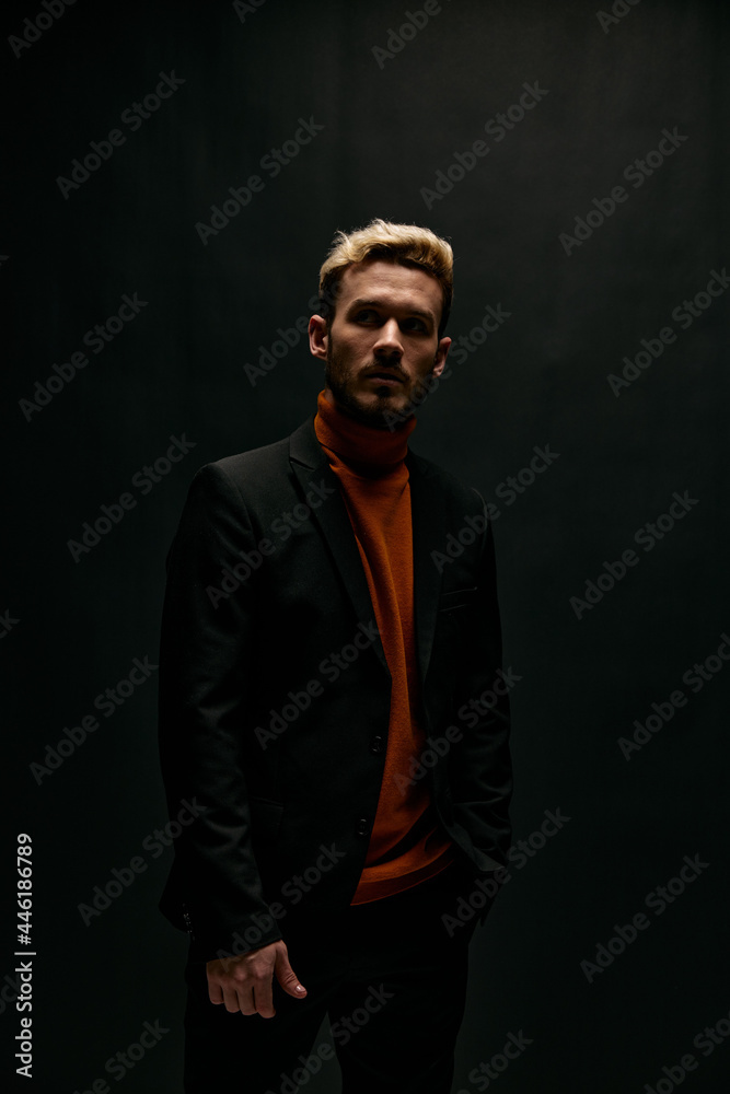 guy on a black background in an orange sweater and leather jacket