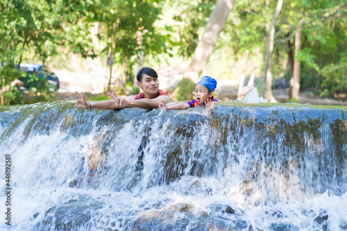Happy Father with daughter enjoy the waterfall. Traveling nature near a beautiful waterfall at Chet Sao Noi waterfall National Park