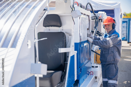 Engineer in hard hat and uniform is servicing hydraulic systems of mining equipment for descending into mine