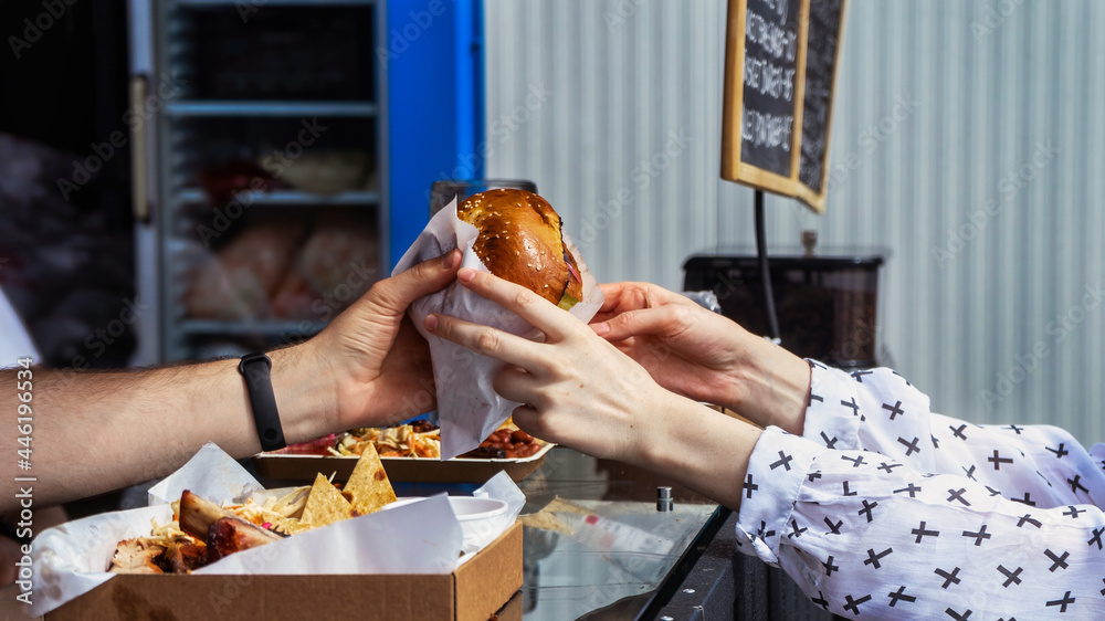 Cook finishing a burger and a client taking it, Food truck