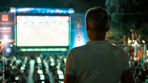 Man watching football in a public place at night
