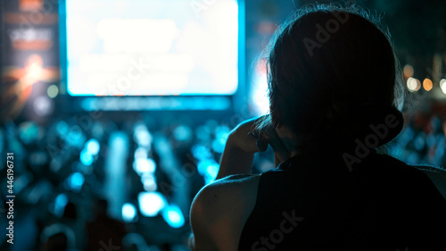 Woman watching football in a public place at night