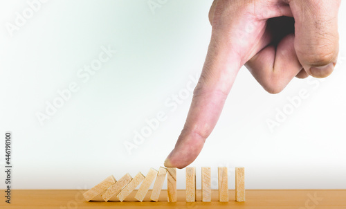 Hand holding domino effect of business crisis or risk protection concept. Business and corporate growth being affected by the crisis