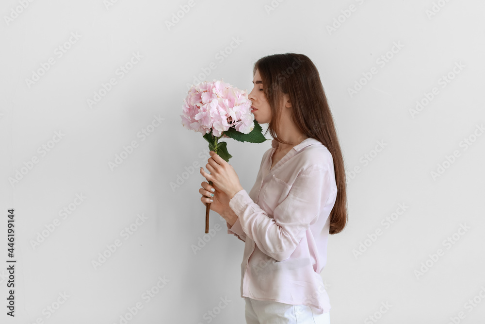Young woman with hydrangea flowers on light background Young woman with hydrangea flowers on light background