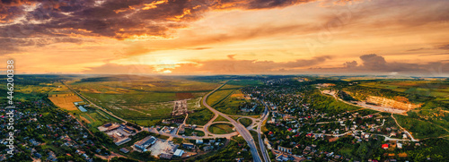 Aerial drone panoramic view of a village and road near it, green fields and hills in the distance, Moldova