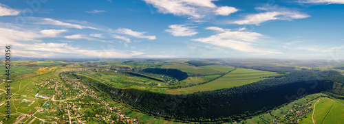 Aerial drone panoramic view of nature, valley with river, hills and fields, multiple greenery, village, Moldova
