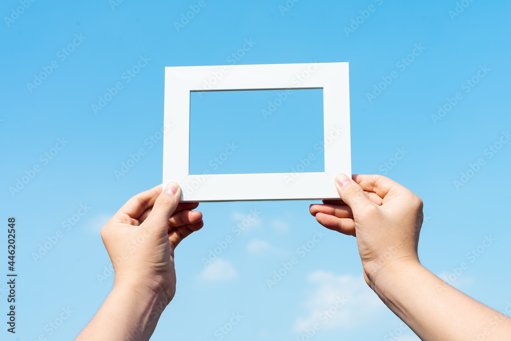 picture of hands holding photo frames on blue sky background