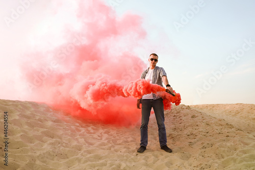 Guy posing with red smoke bomb at the desert