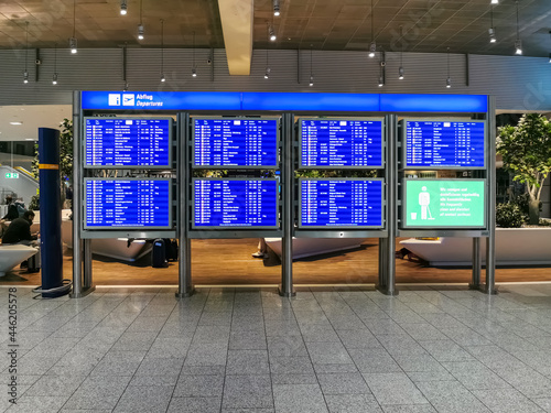 Interior view of the Frankfurt airport building,departure information board and public airport lounge with people waiting as background photo