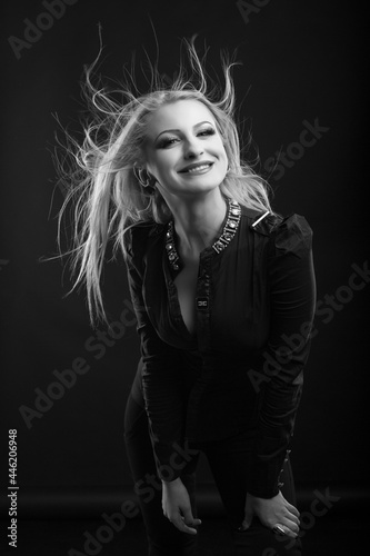 Joyful blond woman with long fluttering hair posing at studio