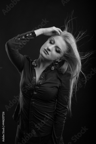 Awesome blond woman with long fluttering hair posing at studio