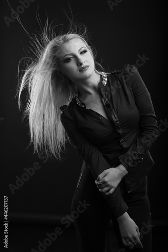 Splendid blond woman with long fluttering hair posing at studio