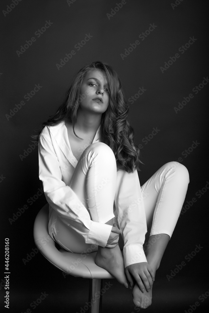 Fashionable model sitting on a chair at dark room Fashionable model sitting on a chair at dark room