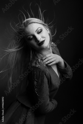 Romantic woman with bright makeup and hair in wind wears jacket