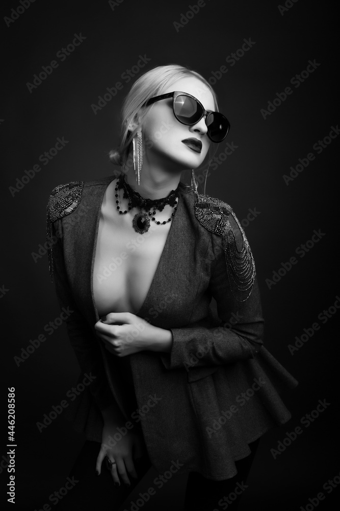 Monochrome studio portrait of a adorable blond woman wears sunglasses and jacket