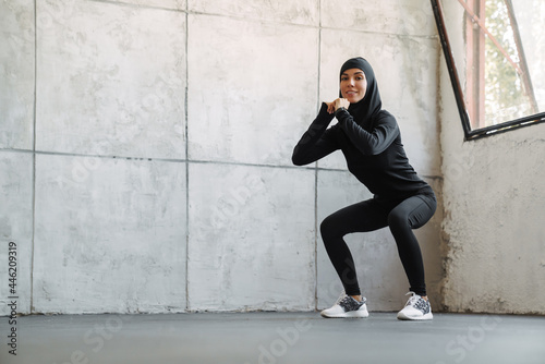 Young muslim woman in hijab doing exercise while working out indoors © Drobot Dean