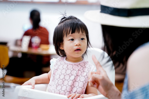 Asian baby girl listening acknowledge to her mother speaking during launch time in restaurant. photo