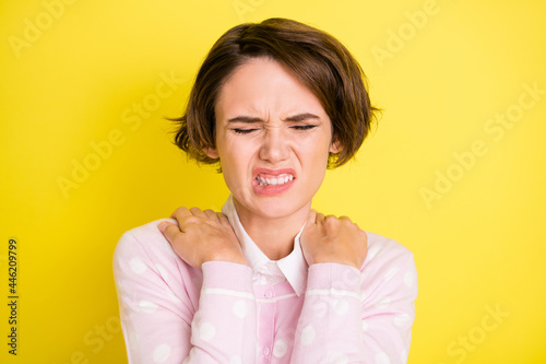 Photo of young girl unhappy sad hands touch shoulders pain suffer ache isolated over yellow color background