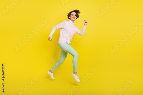 Full length body size photo of cheerful model jumping high running fast smiling isolated vivid yellow color background