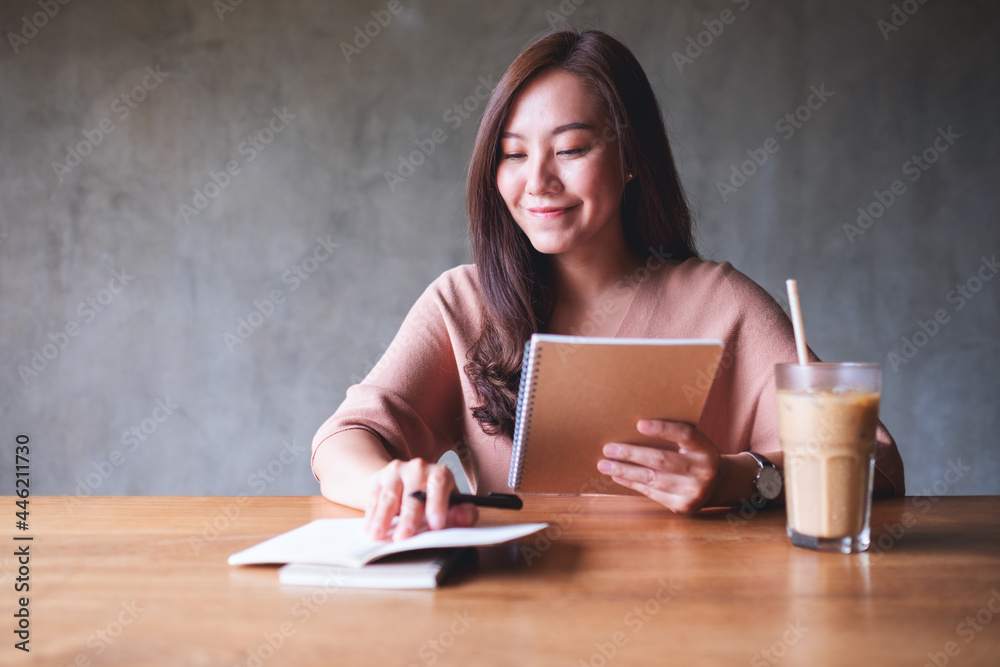 A young asian woman working and writing on a notebook on wooden table A young asian woman working and writing on a notebook on wooden table