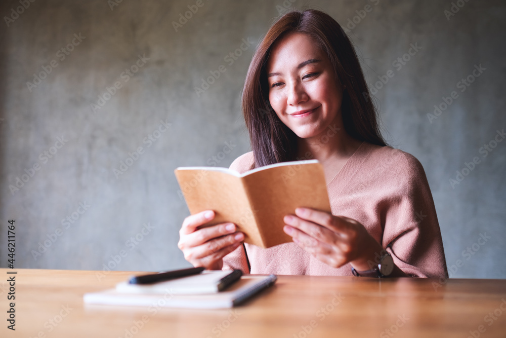 Obraz premium A beautiful young asian woman reading a book