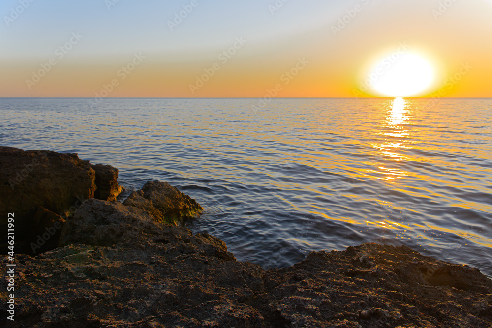 A rocky shore of a calm sea on a summer evening