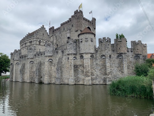 Facade of the Gravensteen medieval ages castle surrounded by water canal. Ghent, East Flanders, Belgium.