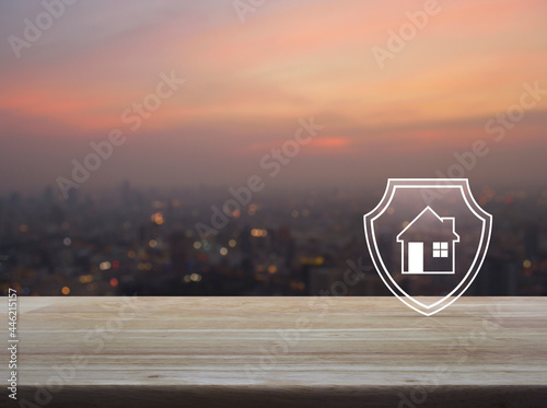 House with shield flat icon on wooden table over blur of cityscape on warm light sundown, Business home insurance and security concept