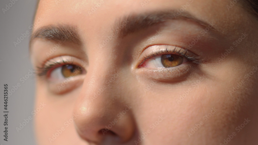 Fototapeta premium Young woman charming brown eyes with mascara. Look in the camera. Studio shot with dramatic light extreme close-up high quality photo portrait.