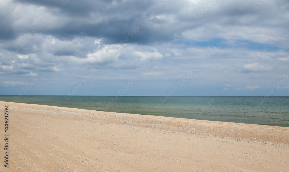 Seascape. Sandy coast and cloudy sky.
