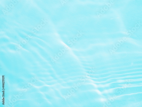 Ripple water texture on blue pool background. Shadow of water on sunlight. Mockup for product, spa or travel background. Marble blue water surface as wallpaper background