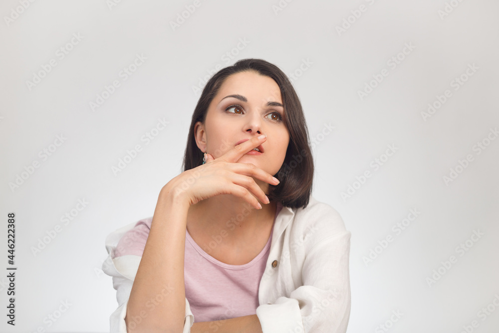 High-key studio portrait of a young dreaming brunette multiethnic woman in light clothes looking into the distance. High-key studio portrait of a young dreaming brunette multiethnic woman in light clothes looking into the distance.