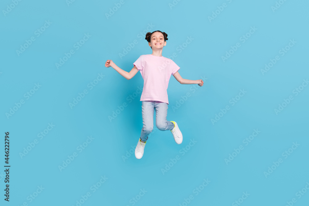 Photo of pretty charming school girl wear pink t-shirt smiling jumping high isolated blue color background