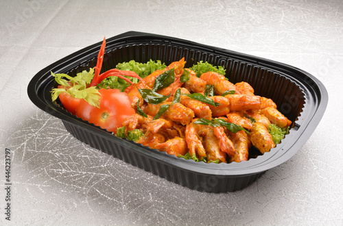 stir fried big tiger prawn with pumpkin creamy sauce and curry leaf in black party bento tray box for asian take away halal menu