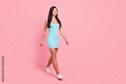 Full size photo of optimistic lady go look empty space wear blue dress sneakers isolated on pink color background © deagreez