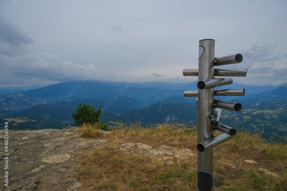 silver-colored metal signpost in the mountains close-up across aerial mountains view. Adventure, travel lifestyle. Pietra di Bismantova, Italy silver-colored metal signpost in the mountains close-up across aerial mountains view. Adventure, travel lifestyle. Pietra di Bismantova, Italy