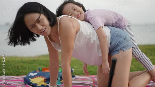Asian Mum and Child playing piggy back next to the beach in 4K real time