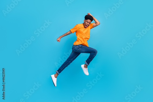 Full length body size view of attractive cheerful funky guy jumping running fast isolated over bright blue color background