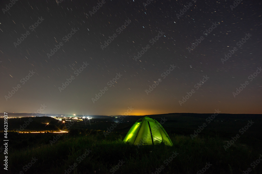 Night landscape tent against the background of the starry sky and city lights