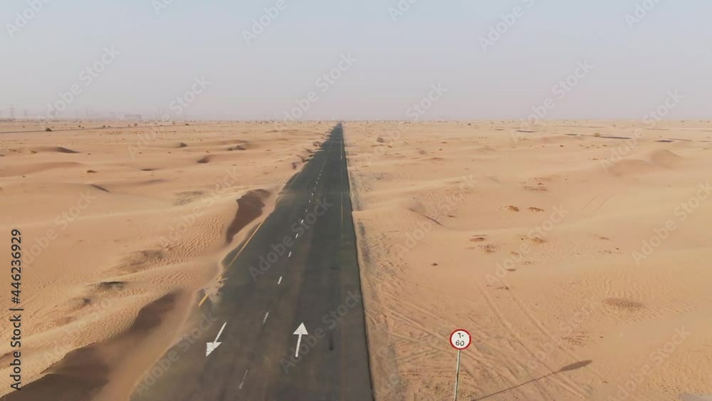 Vertical panning from a quadcopter. White car is driving on road in the desert