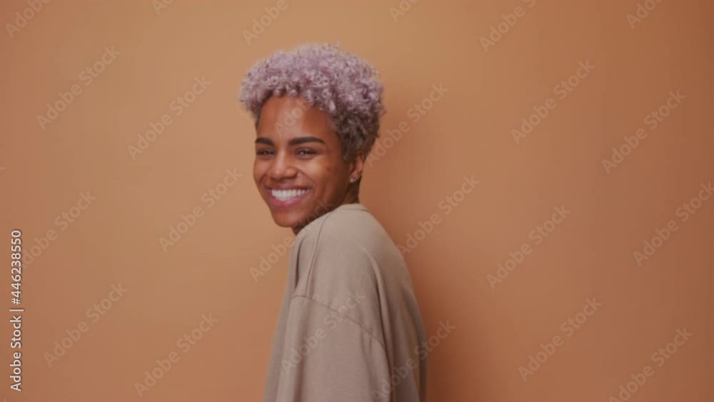 Overemotive African American woman laughs loudly hears funny joke or story, being overjoyed raises palms with satisfaction, dressed in beige t shirt, amused by friend. People and emotions concept.