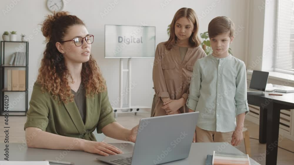 Lecturing Boy Medium long of two guilty Caucasian boy and girl standing by desk of ...
