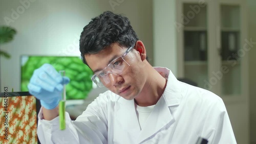 Asian Researcher Looking At Test Tube With Green Dna Of Sapling Analyzing Genetic Mutation Modified For Microbiology Experiment. Scientist Working In Agriculture Laboratory Developing Eco Environment
 photo