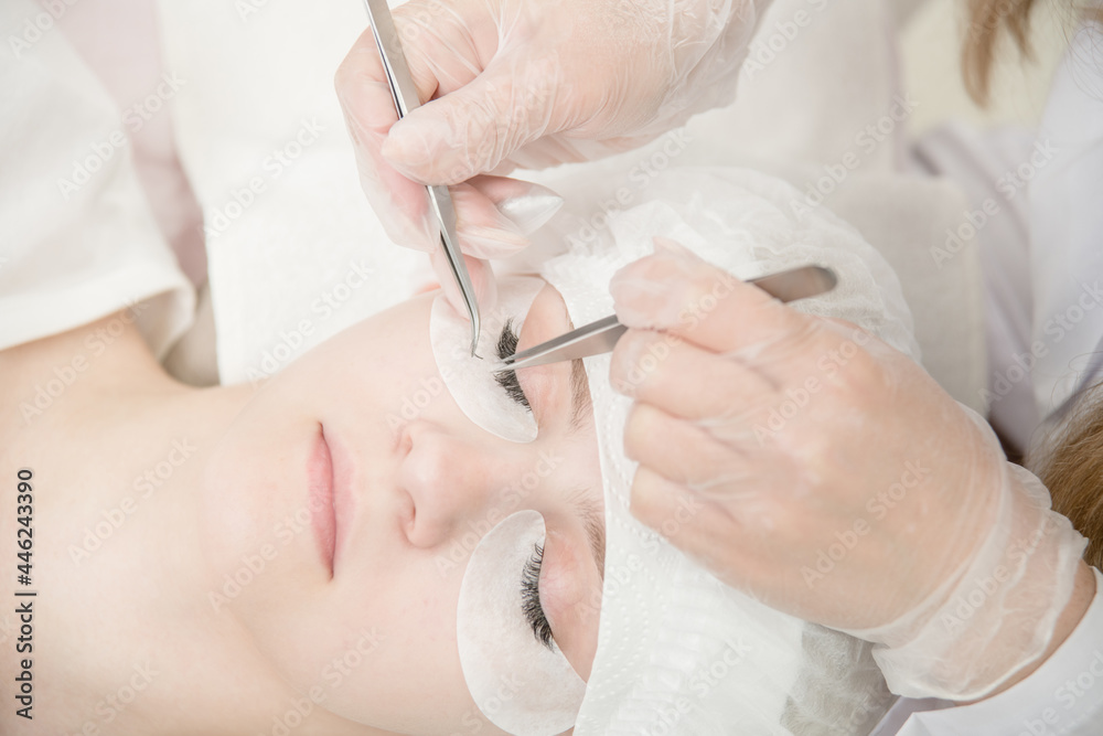 Close up beautiful young woman during eyelash extension at beauty salon Close up beautiful young woman during eyelash extension at beauty salon