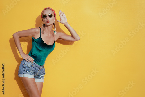 Gossip concept. Colorful portrait of amazed young woman with palm near her ear. Yellow background. © luengo_ua