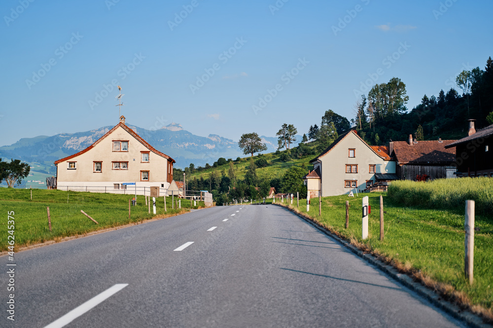 Asphalt road in Alps mountain village. Road trip concept.