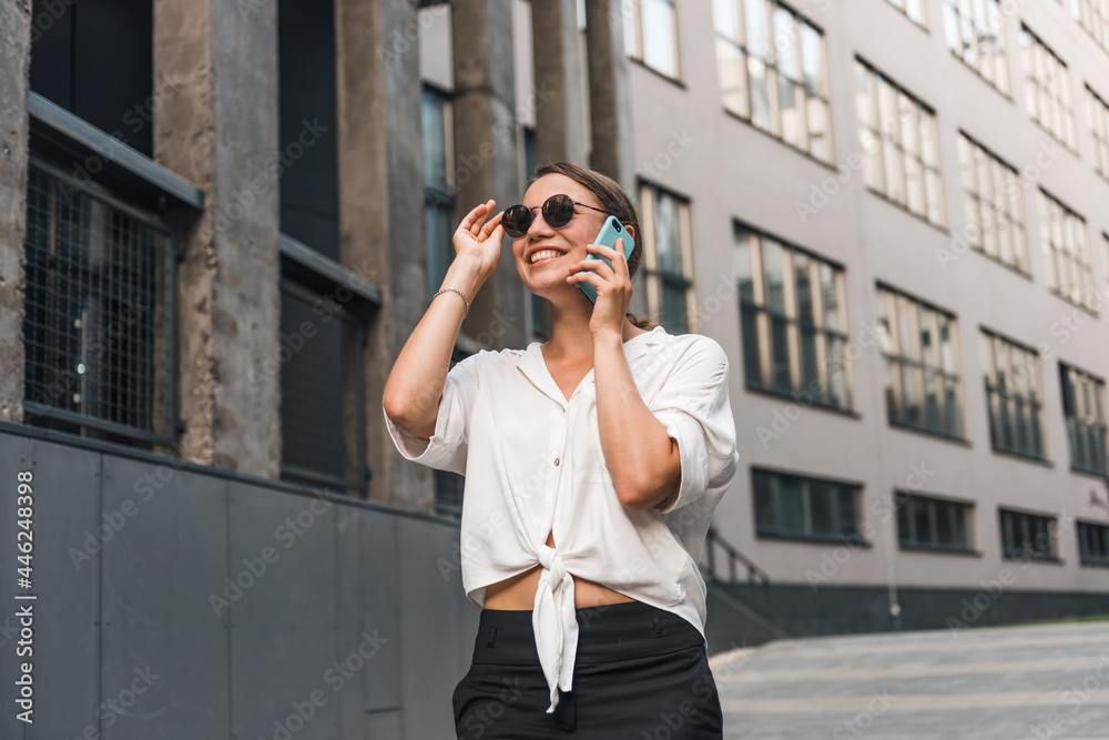Business woman in the city talking on speaker with smartphone. Close up successful woman using phone at street. Business woman in the city talking on speaker with smartphone. Close up successful woman using phone at street.